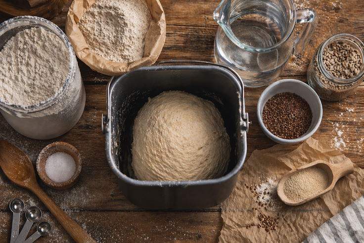 Ингредиенты для домашнего хлеба и тесто в хлебопечке Ингредиенты для домашнего хлеба и тесто в ведёрке хлебопечки